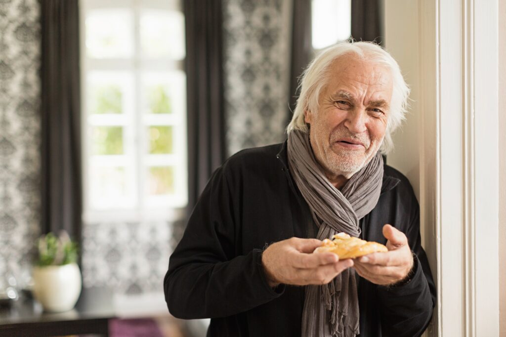 Senior man holding danish pastry